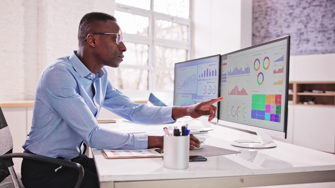 IFC consultant analysing financial data across dual monitors